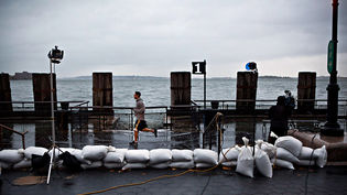 Un home corre rere el material de rodatge d'una emissora de notícies que rodava a Battery Park durant l'arribada de l'huracà Sandy/ GETTY IMAGES/ Andrew Burton
